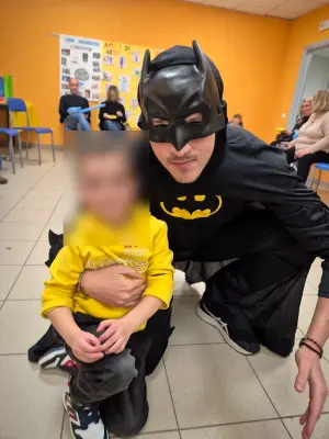 Batman in ginocchio accanto al festeggiato con la felpa gialla