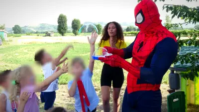 I bambini saltano per prendere le bolle di sapone con Spiderman e l'animatrice