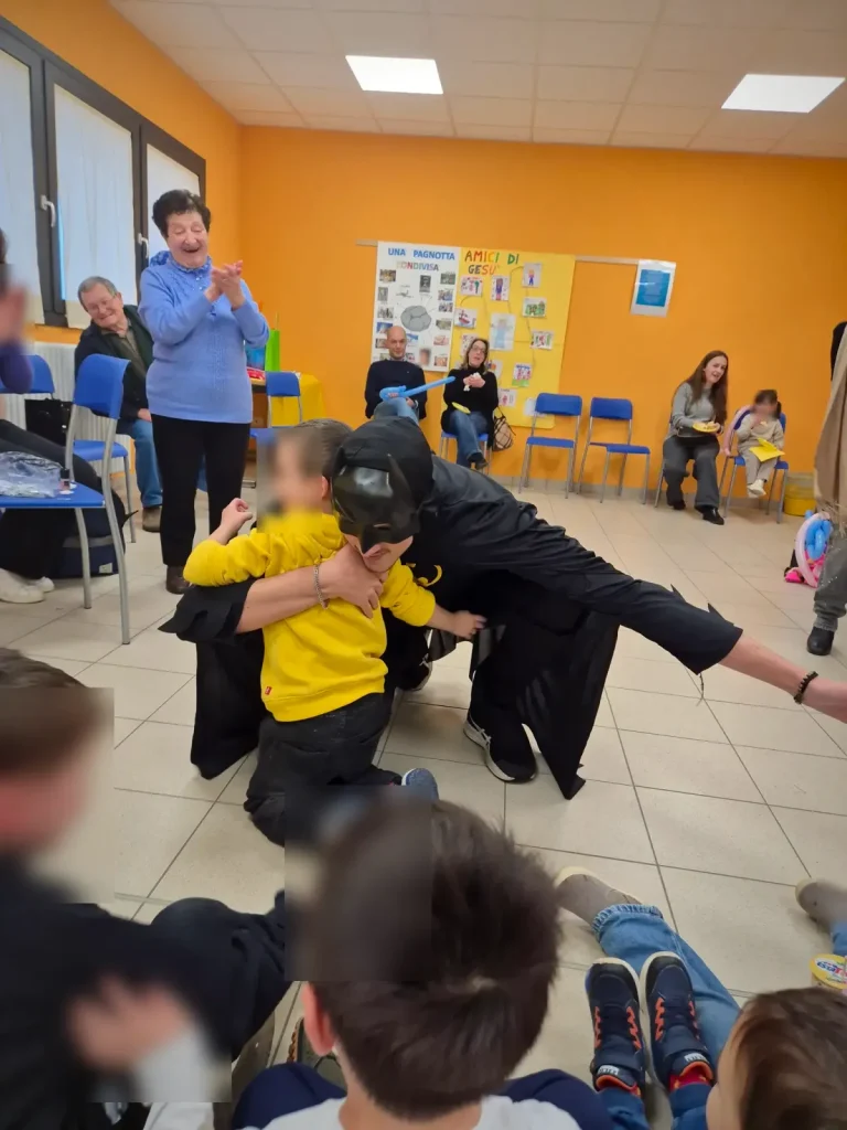 Batman abbraccia il festeggiato, con i nonni e gli invitati alle spalle