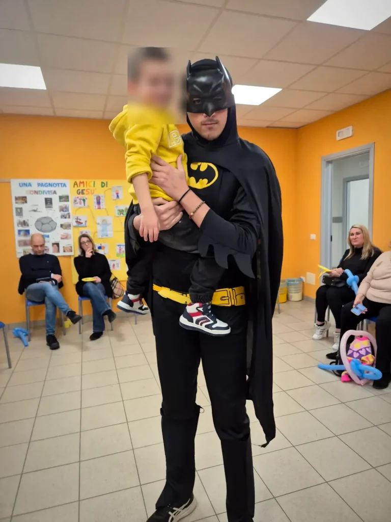 Batman tiene in braccio il festeggiato nella sala della festa