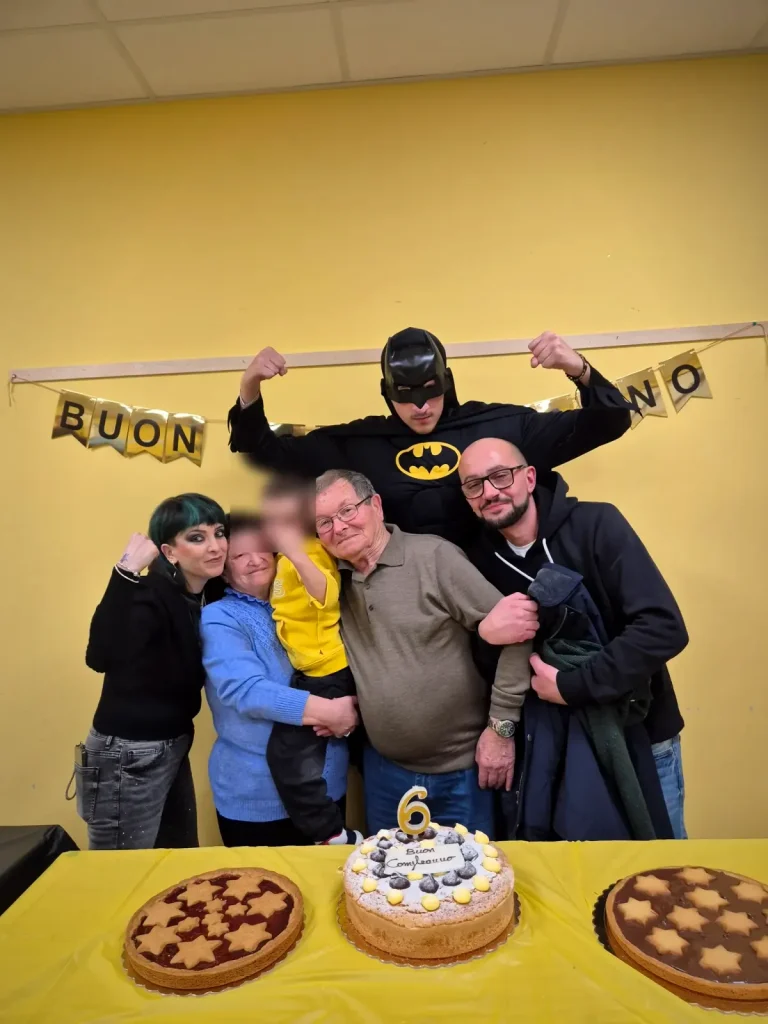 Il festeggiato con la famiglia e Batman dietro la torta con la candelina del sei