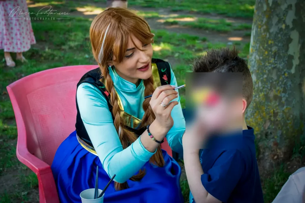 Anna dipinge il viso di un bambino al tavolo del truccabimbi