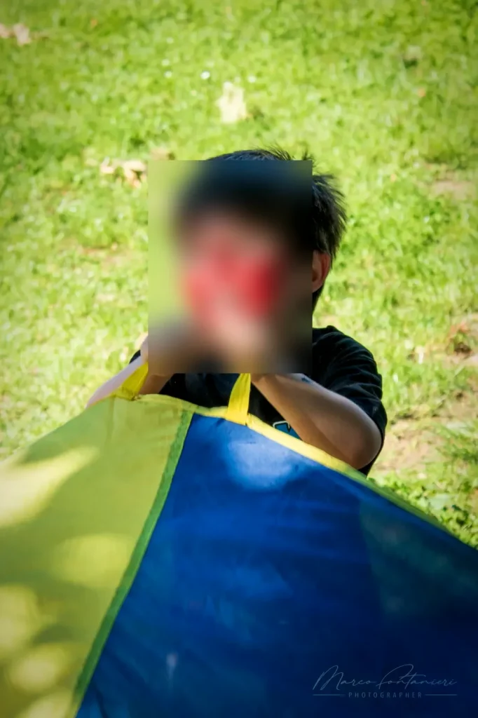 Un bambino con il trucco di Spiderman gioca con il paracadute colorato