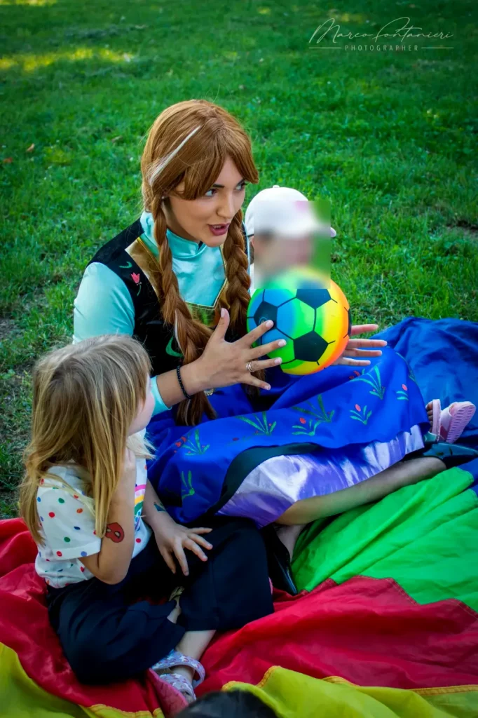 Anna con il paracadute e il pallone, insieme ai bambini sul prato