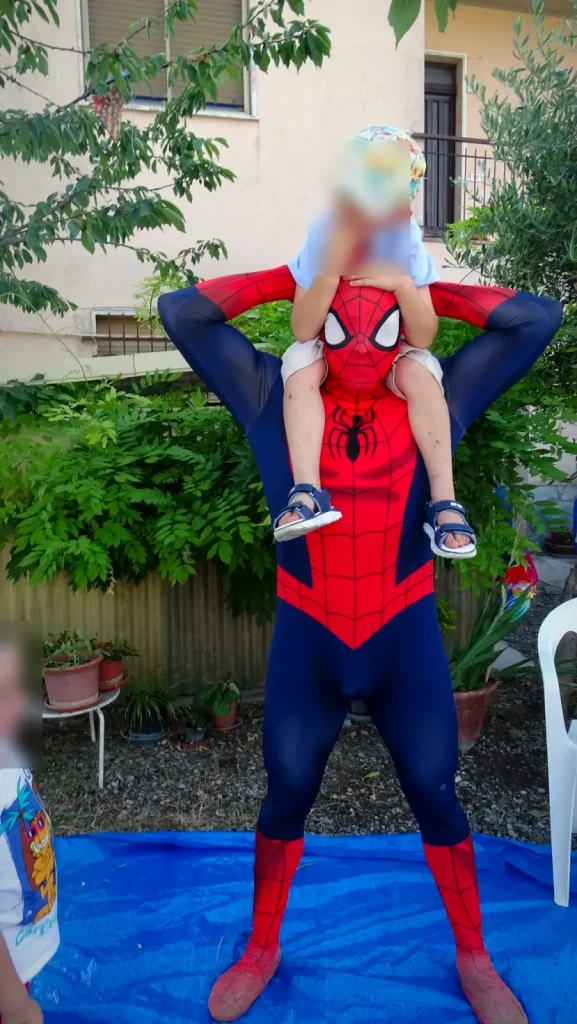 Spiderman porta un bambino sulle spalle nel giardino della festa