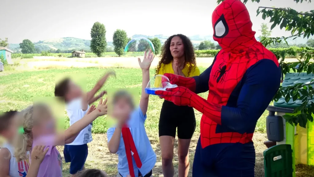 I bambini saltano per prendere le bolle di sapone con Spiderman e l'animatrice